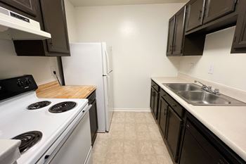 An empty kitchen with a stove sink and refrigerator